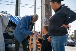 homeless man fist bumps boy